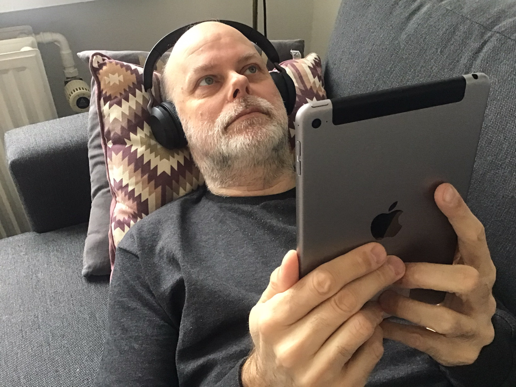 Kristian Marcussen liggende på sofa med iPad og hovedtelefoner
